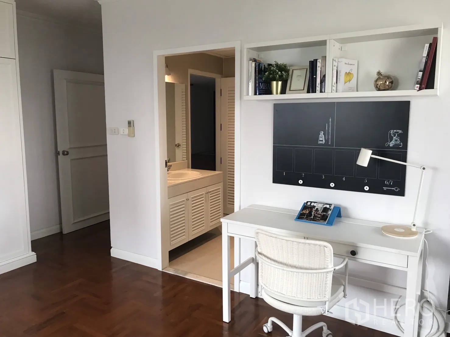 Condominium for rent in Bangkok - Study nook with desk and shelving next to the entrance to an ensuite bathroom.