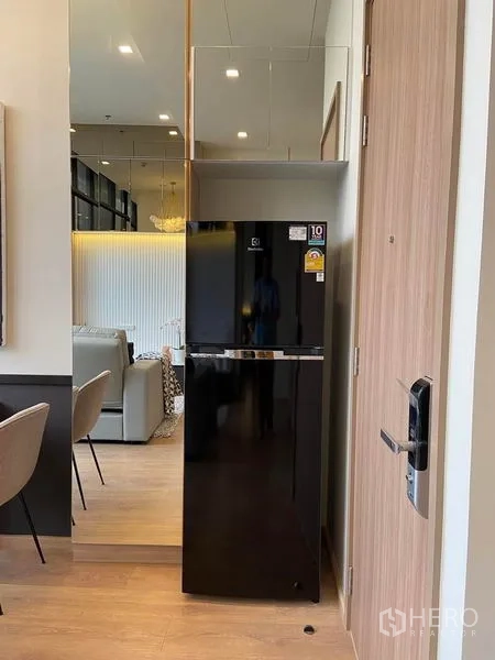 คอนโด ให้เช่าในWatthana, Bangkok - มุมทางเข้า มีตู้เย็นสีดำสูงข้างประตูไม้และตู้กระจก