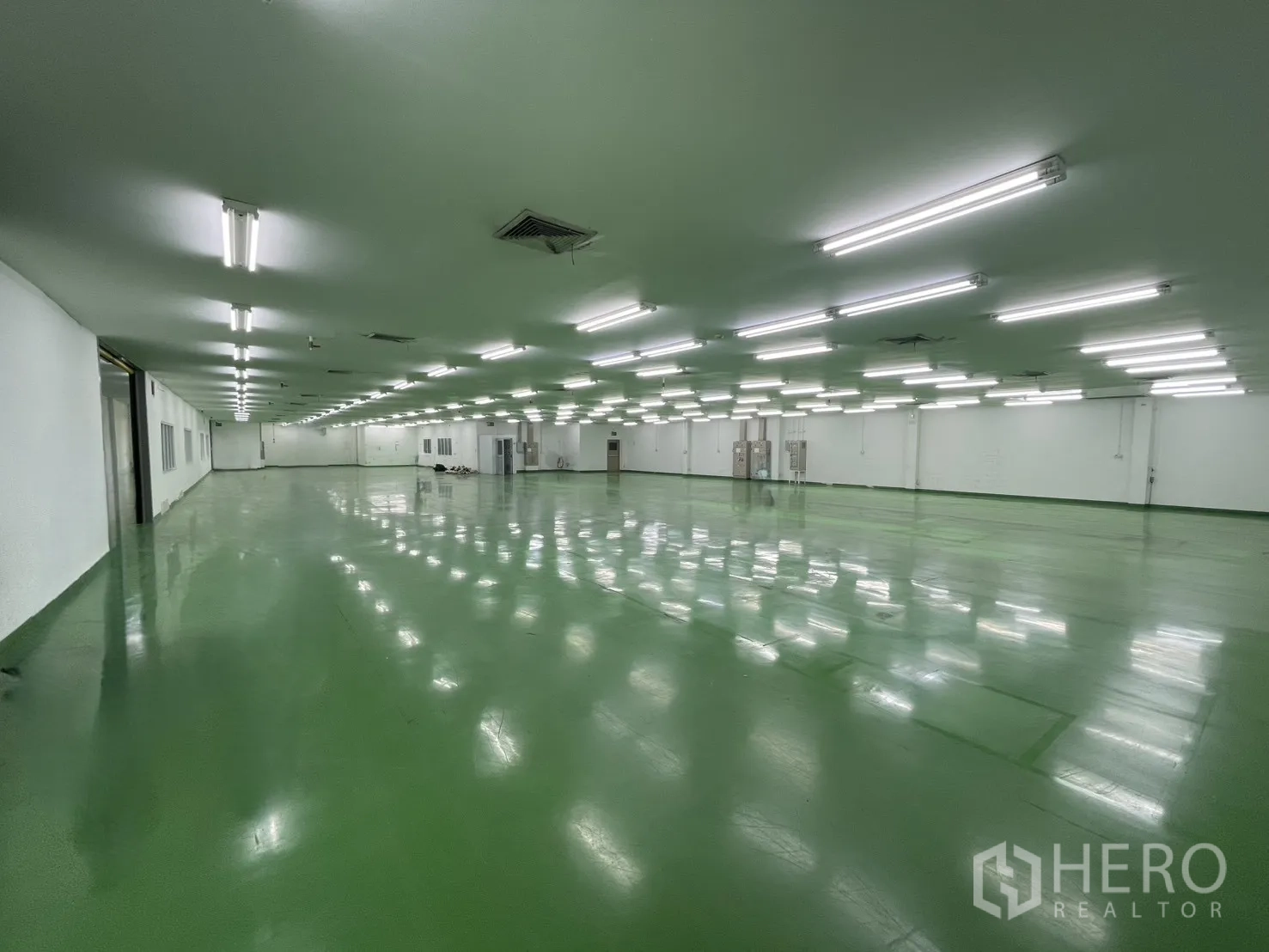 工厂 for rent in Mueang Samut Prakan, Samut Prakan - 宽阔生产大厅，反光绿色地面、天花通风口与成排条形灯。