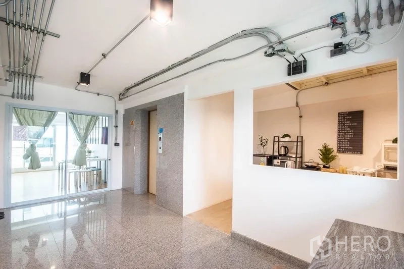 Home Office for rent in Phaya Thai, Bangkok - Bright lobby with elevator, exposed conduits and glass door opening to a meeting area.