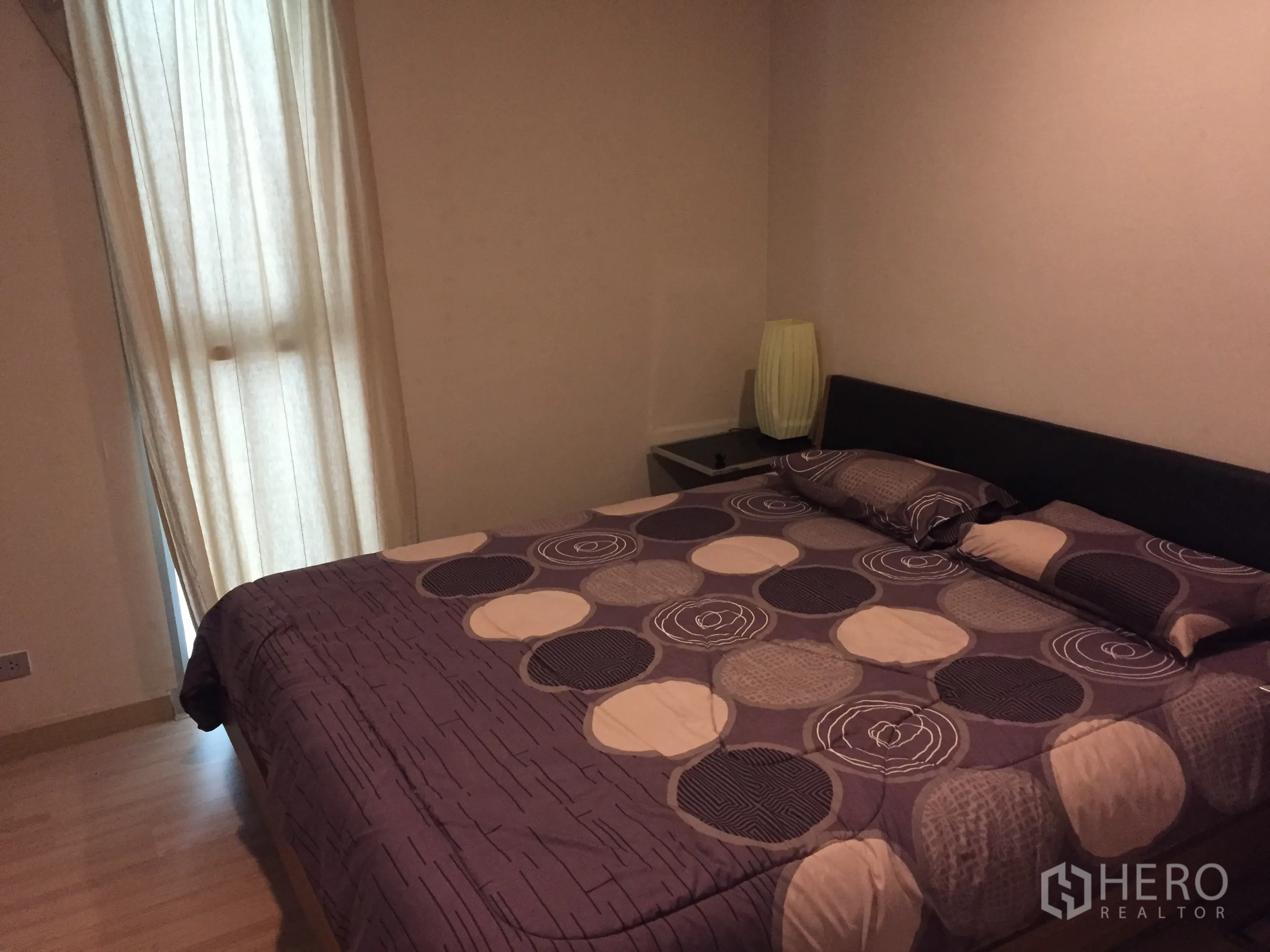 公寓 出租在Watthana, Bangkok - 卧室配大床、几何图案床品、床头灯与温暖木地板。