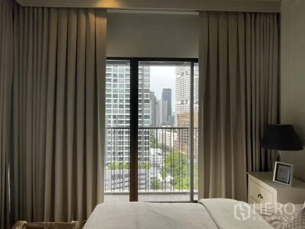 คอนโด ให้เช่าในBangkok - ห้องนอนมีผ้าม่านเต็มบานและระเบียงมองเห็นสกายไลน์กรุงเทพฯ