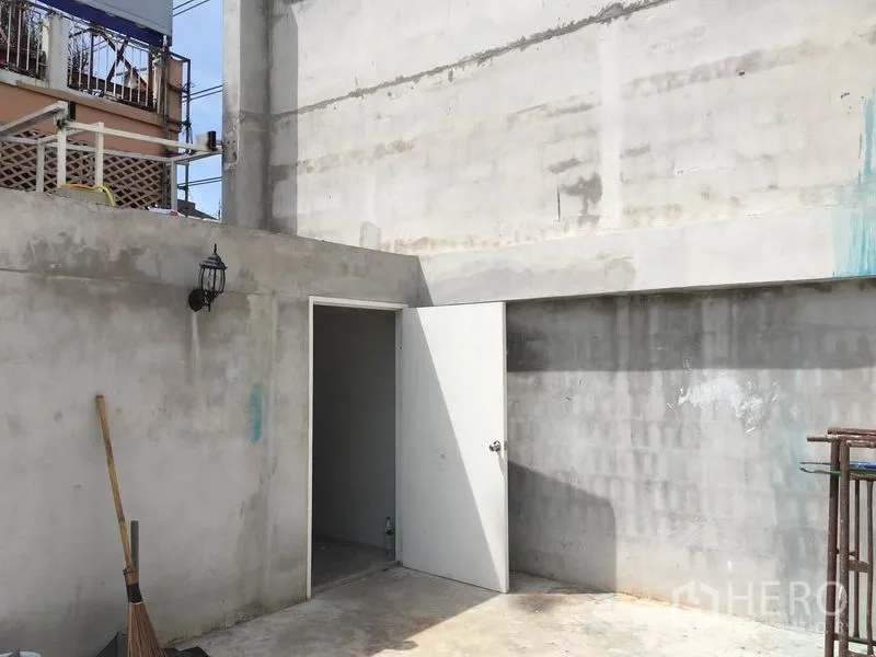 零售空间 出租在Huai Khwang, Bangkok - 混凝土后场服务区，白色门通向储物间，带室外壁灯。