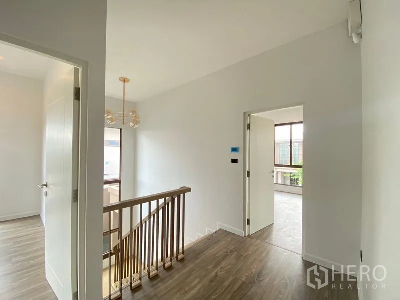 Detached House for rent in Bang Kapi, Bangkok - Upper landing with staircase railing, chandelier and bedroom doors.