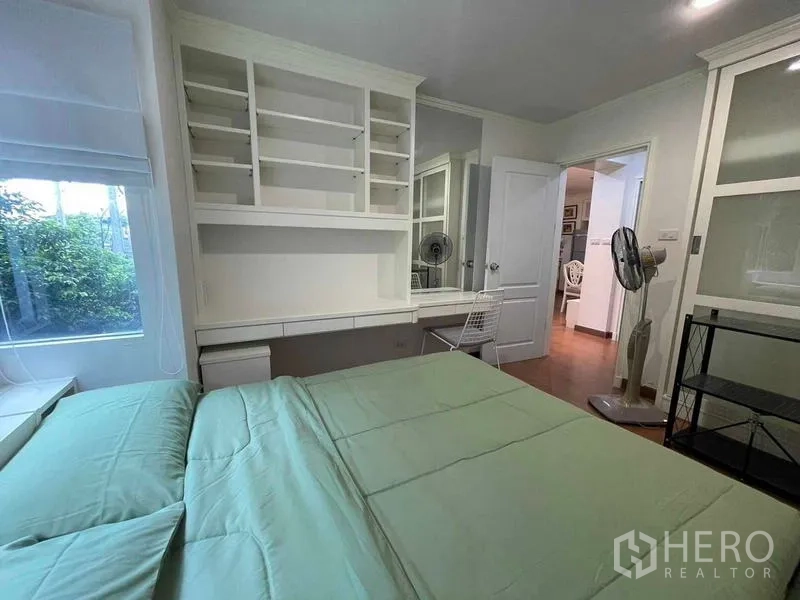Condominium for rent - Bedroom angle showing work desk, shelving and window overlooking greenery.