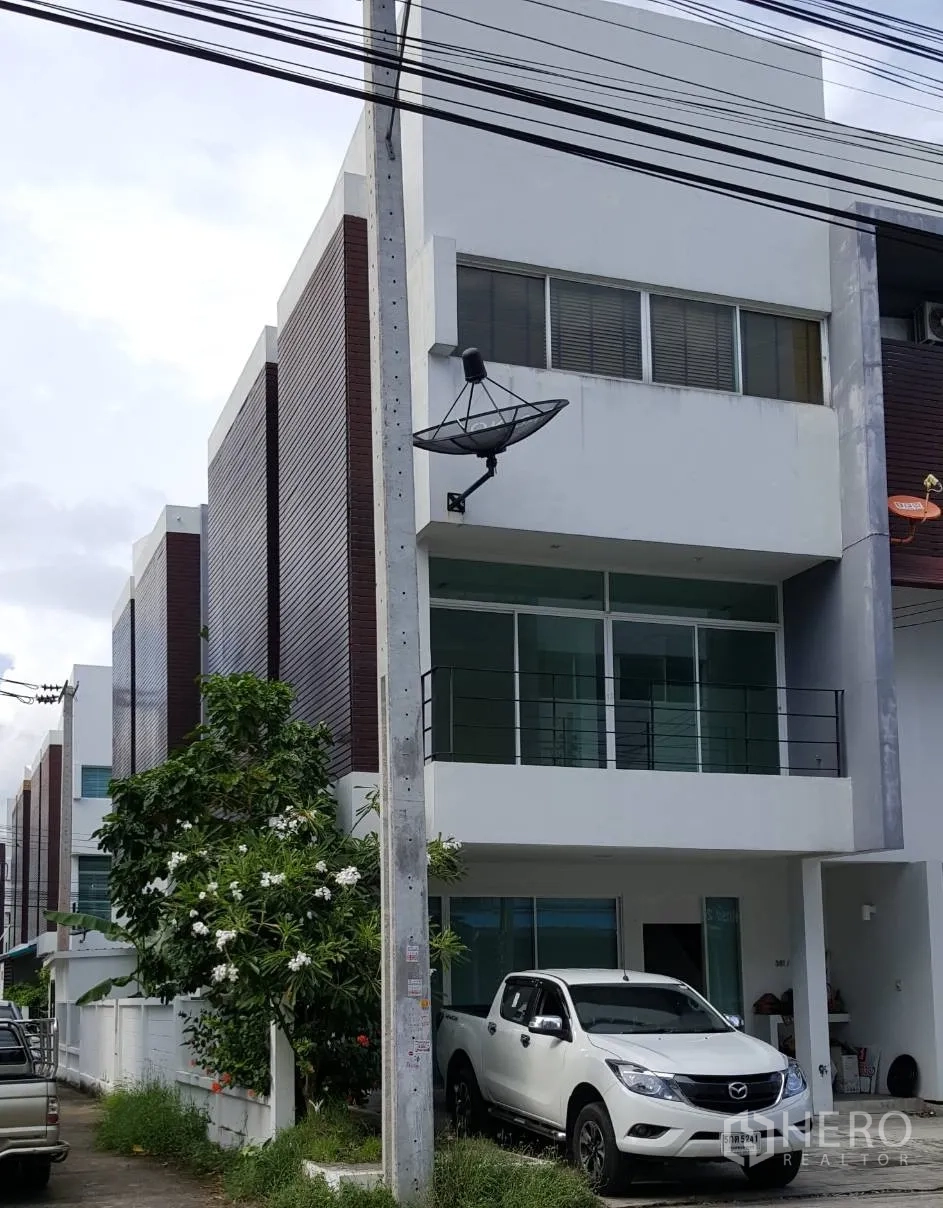 公寓 出租在Pathum Wan, Bangkok - 现代联排式建筑，玻璃立面与阳台，停着皮卡和卫星天线