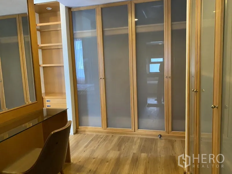 Condominium for rent or sale in Sathon, Bangkok - Dressing area with glass-front wardrobes, built-in desk and wood flooring.
