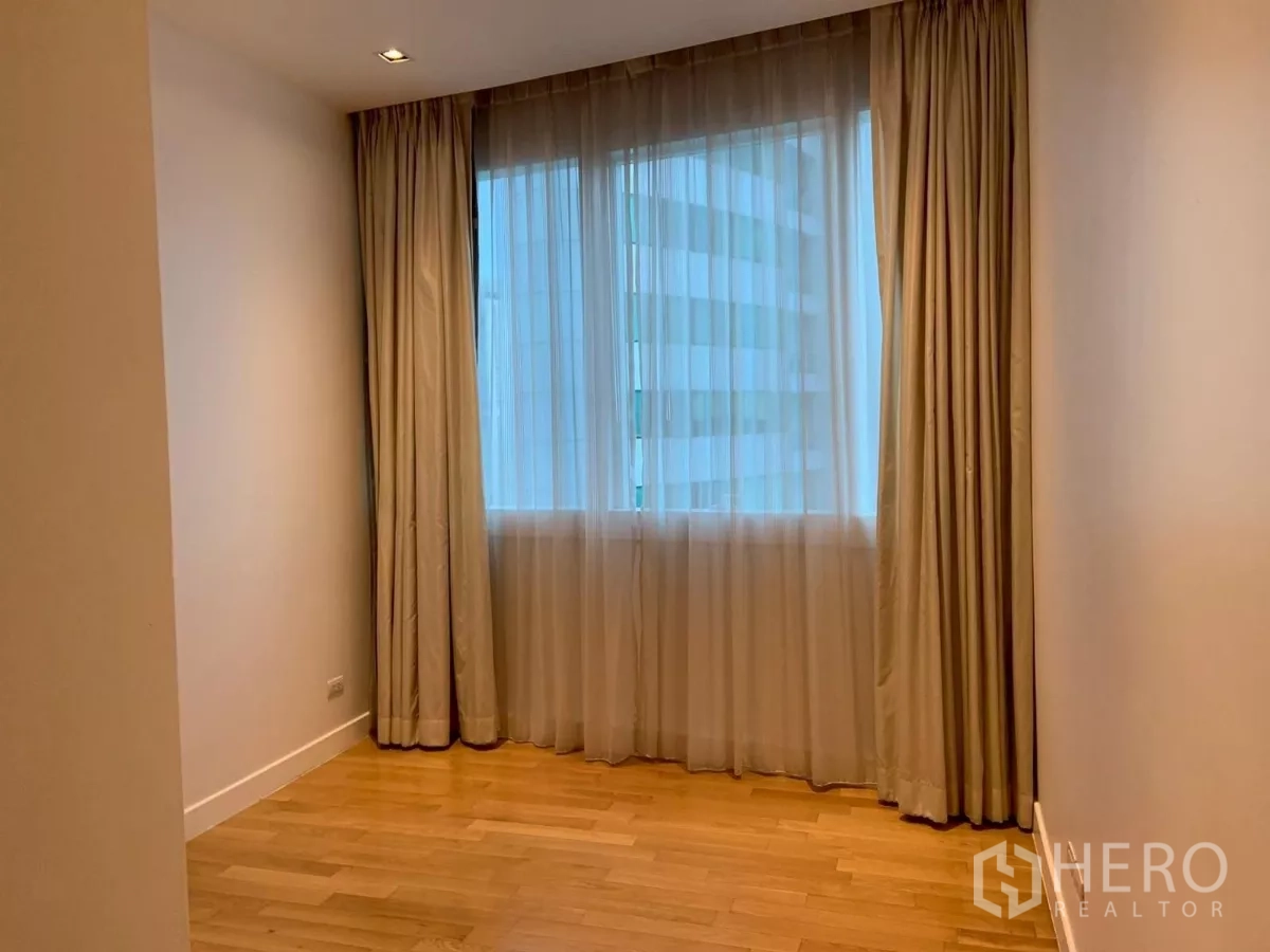 Condominium for rent in Khlong Toei, Bangkok - Secondary bedroom with large window and drapes.