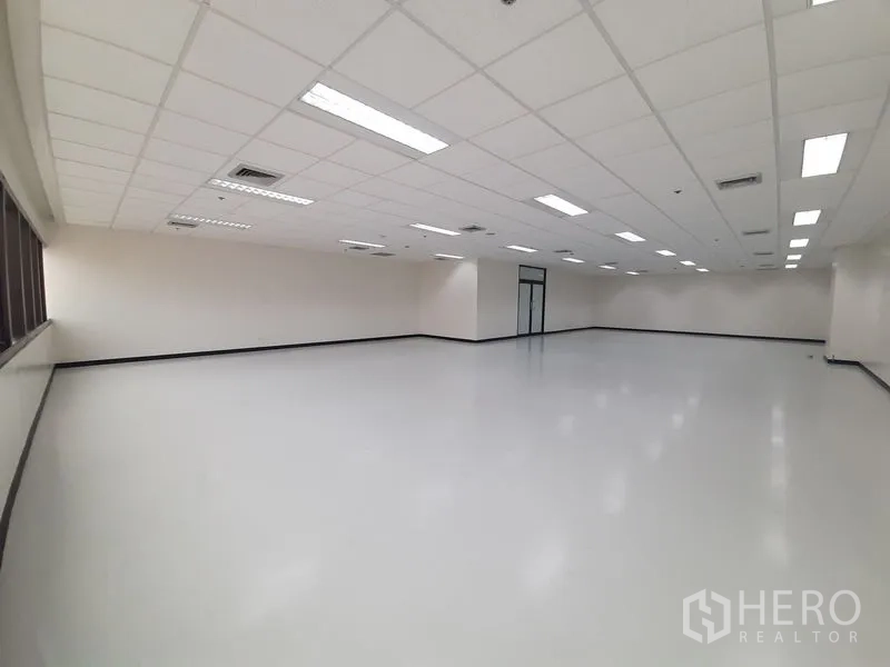 Office Space for rent in Bang Rak, Bangkok - Spacious office floor with suspended ceiling lights and a continuous band of windows on one side.