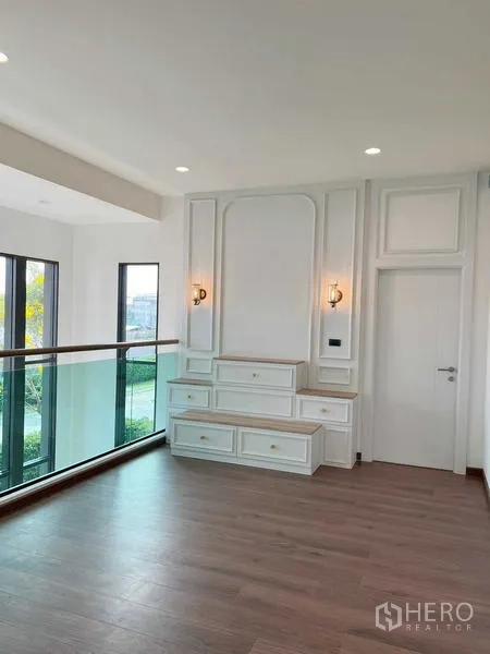 独立式住宅 出售在Bangkok Noi, Bangkok - 二层平台设白色定制柜与玻璃栏板，可俯瞰客厅。