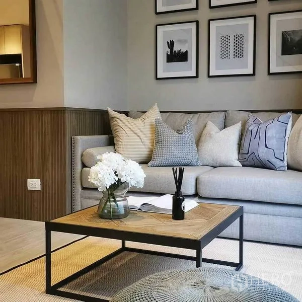 Condominium for rent in Bang Rak, Bangkok - Modern Silom condo living room with grey sofa, cushions, wood coffee table and framed wall art.