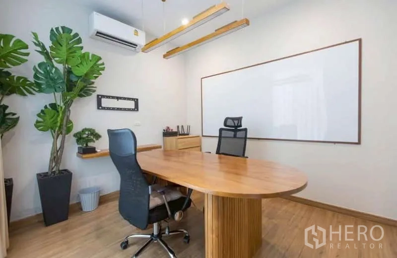 Detached House for rent or sale in Lat Phrao, Bangkok - Home office with long wood desk, whiteboard and potted plants.
