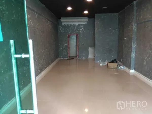 Retail Space for rent in Huai Khwang, Bangkok - Empty retail unit with tiled floor, dark ceiling and recessed lights leading to a back doorway.