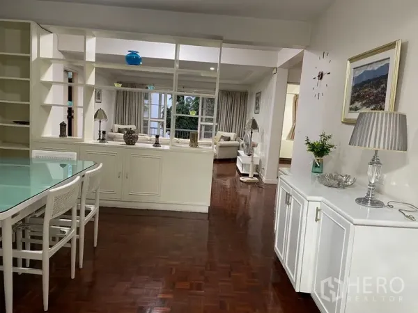 Apartment for rent in Watthana, Bangkok - Open-plan dining and living area with parquet flooring and partition shelving.