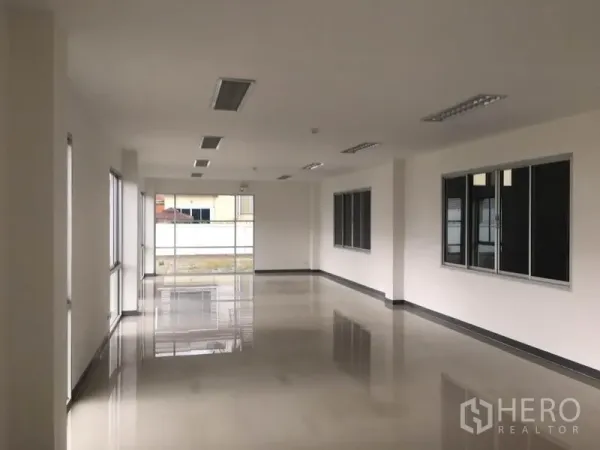 Factory for rent in Samut Prakan - Bright office floor with polished tiles, ceiling lights and wide windows overlooking the compound.