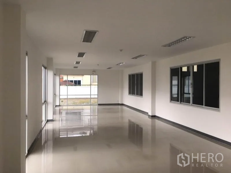 Factory for rent in Samut Prakan - Bright office floor with polished tiles, ceiling lights and wide windows overlooking the compound.