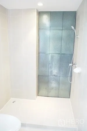 Condominium for rent in Pathum Wan, Bangkok - Bright bathroom with walk-in shower and textured glass partition.