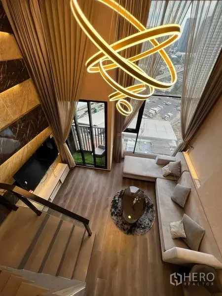 公寓 出售在Chatuchak, Bangkok - 从阁楼俯瞰双层挑高客厅，环形吊灯、阳台与城市天际线。