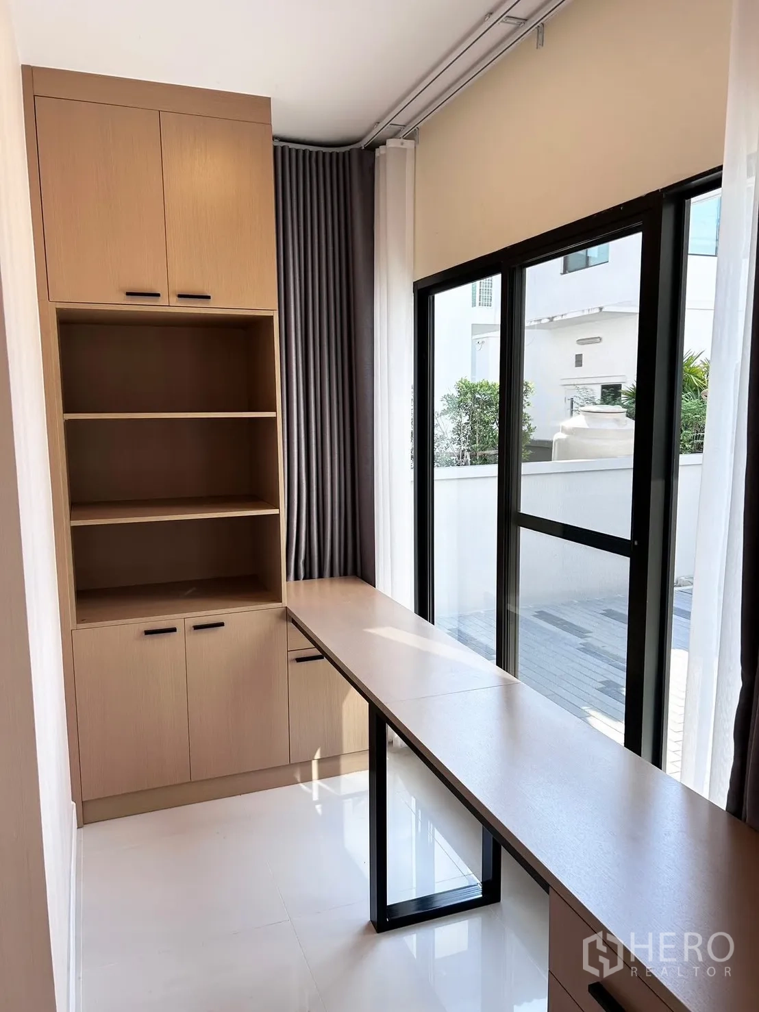 独栋房屋 for rent or sale in Prawet, Bangkok - 紧凑书房，超长内置书桌与柜体，推拉玻璃门通向庭院。
