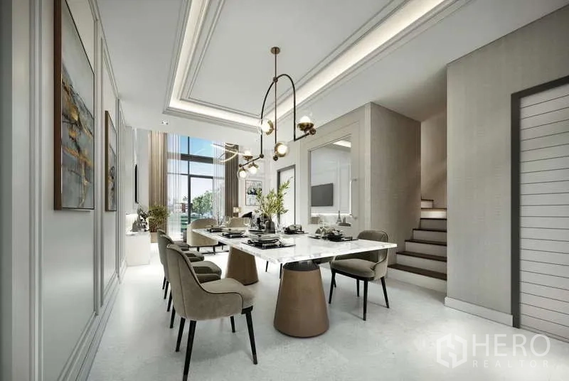 Townhouse for sale - Bright dining area with a long marble table, designer pendant lights and a staircase beside tall windows.