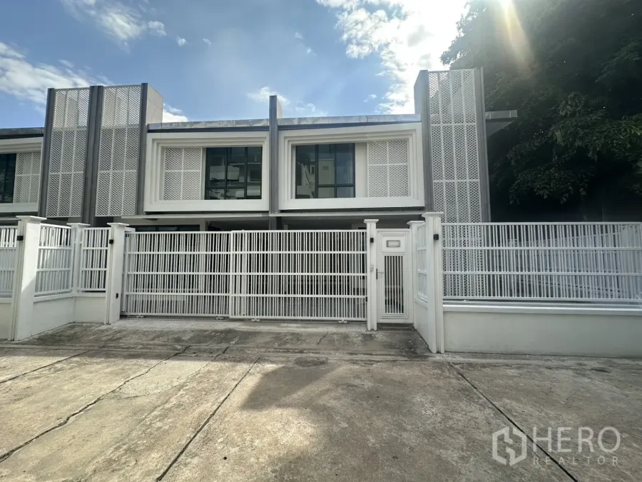 Townhouse for rent in Watthana, Bangkok - Modern two-storey townhouse facade with white metal gate and driveway in Watthana, Bangkok.