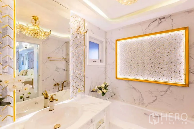 Townhouse for rent in Lat Phrao, Bangkok - Luxurious bathroom with marble tiles, illuminated mosaic feature and gold accents.