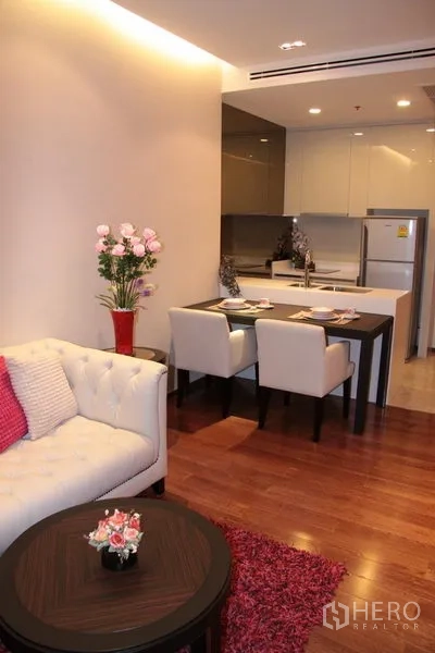 Condominium for rent in Khlong Toei, Bangkok - Compact living room with sofa and round coffee table beside the dining area and kitchen.