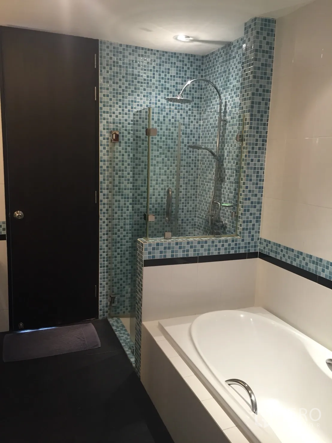 Condominium for rent in Khlong Toei, Bangkok - Main bathroom featuring a soaking bathtub and separate glass rain shower with blue mosaic tiles.