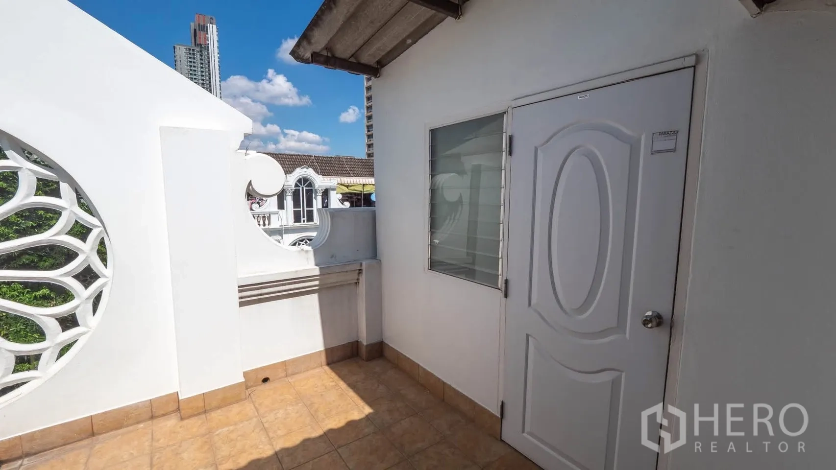 ทาวน์เฮาส์ for rent in Watthana, Bangkok - ระเบียงชั้นบนปูกระเบื้อง มีผนังช่องลายวงกลม ประตูสีขาว ท้องฟ้าแจ่มใส