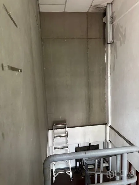 Shophouse for rent in Khlong Toei, Bangkok - Industrial stairwell with high ceiling, metal handrail and a ladder for maintenance.