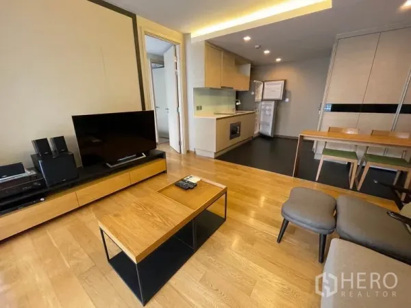 公寓 出售在Watthana, Bangkok - 开放式客厅，前方茶几与电视，后方为紧凑厨房。