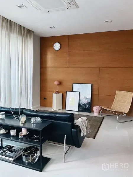 Detached House for sale in Bang Kapi, Bangkok - Bright living room with wood accent wall, sheer curtains, and modern lounge seating.