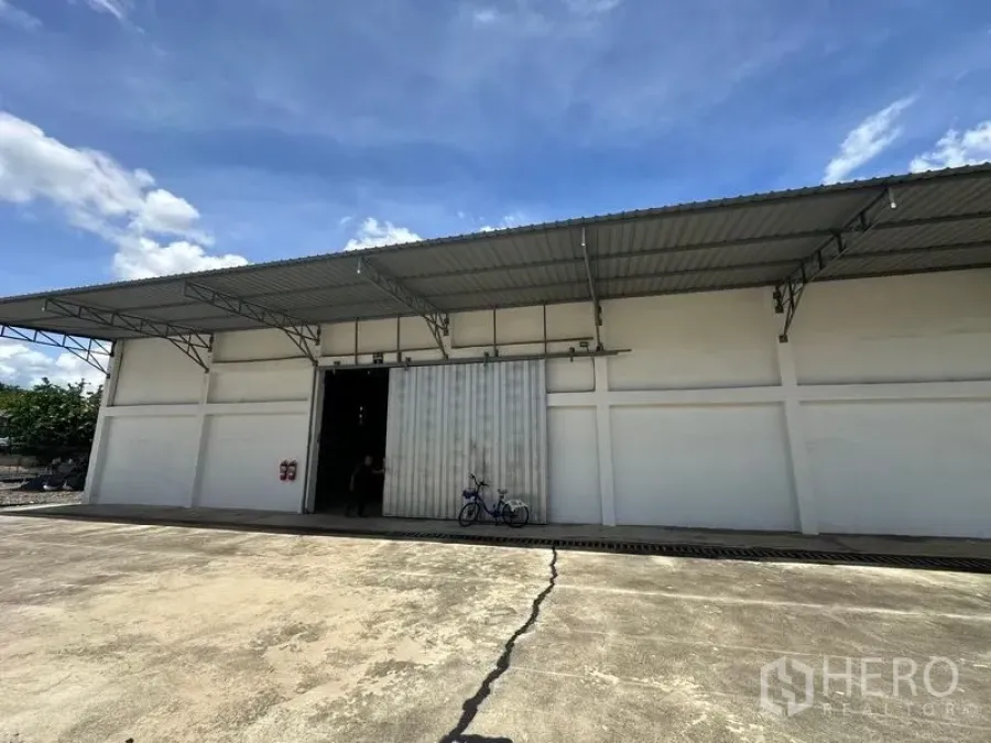 Warehouse for rent in Mueang Pathum Thani, Pathum Thani - Wide interior shot of the warehouse featuring steel roof trusses, concrete flooring and open entry.
