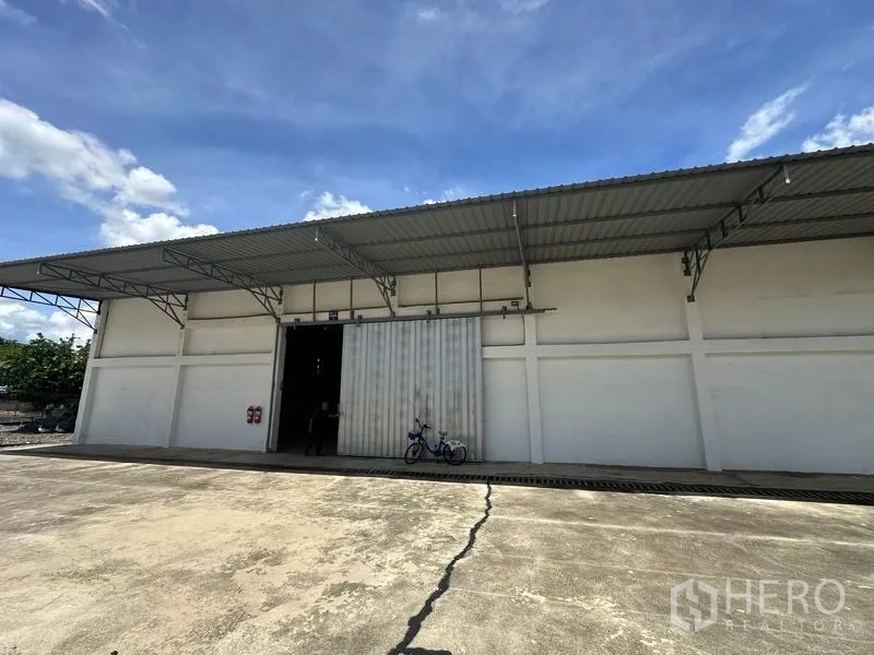 Warehouse for rent in Mueang Pathum Thani, Pathum Thani - Wide interior shot of the warehouse featuring steel roof trusses, concrete flooring and open entry.