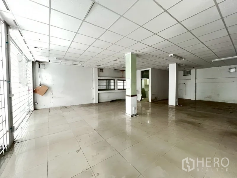 Shophouse for rent in Phra Khanong, Bangkok - Open-plan shop floor with columns, drop ceiling and a service counter at the rear.