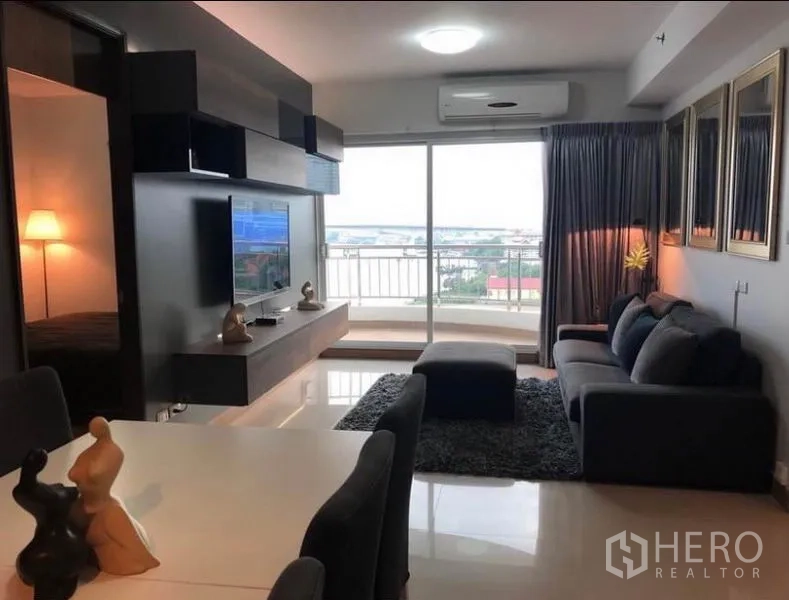 คอนโด ให้เช่าในBangkok - ห้องนั่งเล่นแบบโอเพ่นพร้อมโซฟา ผนังทีวี และโต๊ะทานอาหาร เชื่อมสู่ระเบียงวิวเมืองและแม่น้ำ