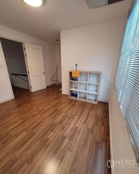 Townhouse for sale in Bang Kapi, Bangkok - Bright spare room with wood floor, window blinds and cube shelving.