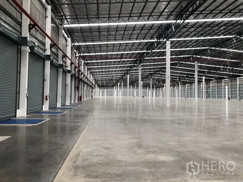 Factory for rent in Wang Noi, Phra Nakhon Si Ayutthaya - Warehouse interior showing a row of motorized roller shutters and expansive floor space.