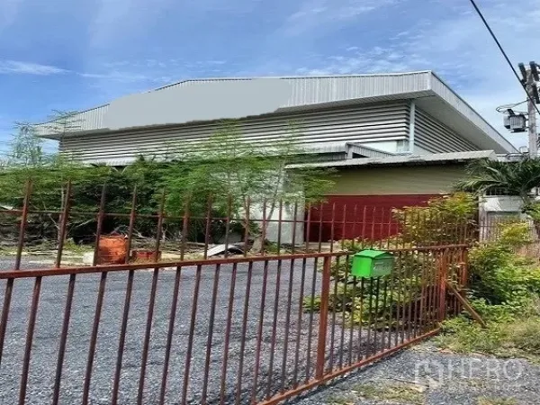 Factory for sale in Khlong Luang, Pathum Thani - Gated entrance to a metal‑clad factory with driveway and greenery in Khlong Luang.