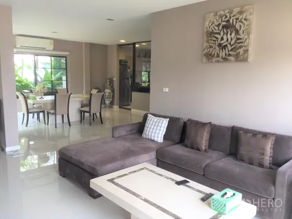 独立式住宅 出租或出售在Prawet, Bangkok - 明亮的客餐一体空间，L形沙发、亮面地砖与大窗户观景。