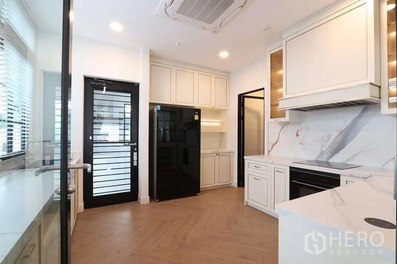 Detached House for rent in Saphan Sung, Bangkok - Kitchen corner showing built-in oven, pantry shelves and pass-through window to dining room.