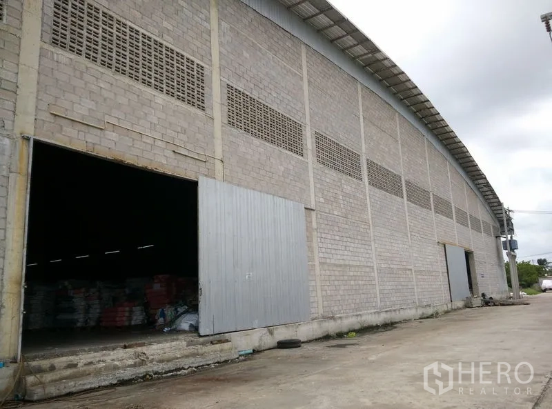 โรงงาน ให้เช่าหรือขายในKrathum Baen, Samut Sakhon - หน้ากว้างอาคารโกดัง ประตูบานเลื่อนโลหะหลายจุด พร้อมลานคอนกรีตกว้างรองรับรถบรรทุก