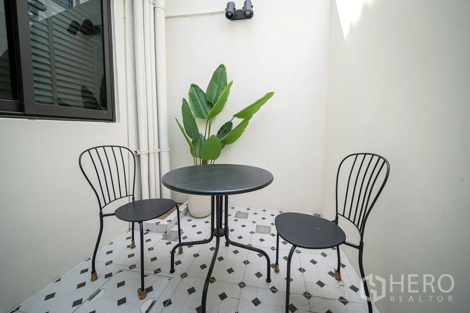 Townhouse for rent in Bang Phli, Samut Prakan - Sunny private patio with a round table, two chairs and a potted tropical plant.