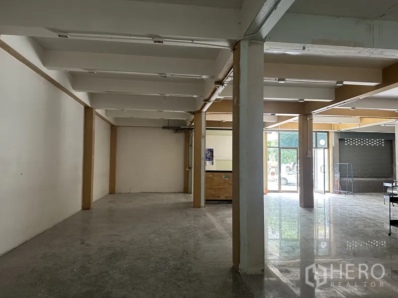 Retail Space for rent in Bang Rak, Bangkok - Side view of the long interior showing beams, columns, and the bright front glass doors.