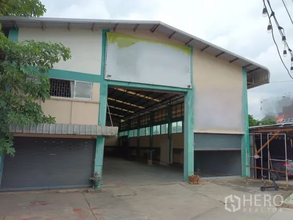 Warehouse for rent in Phasi Charoen, Bangkok - Warehouse front facade with wide entrance, roller shutters and driveway.
