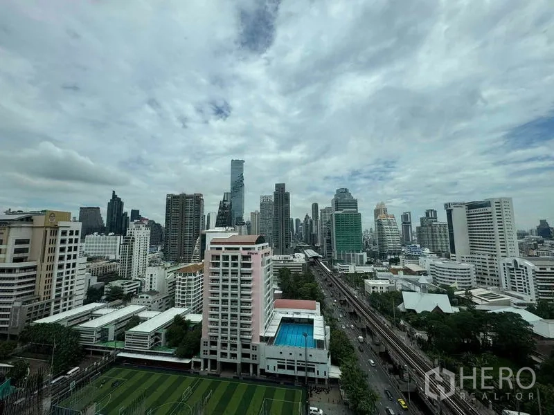 公寓 出售在Bang Rak, Bangkok - 高层全景城市天际线，可见轻轨、运动场与泳池。