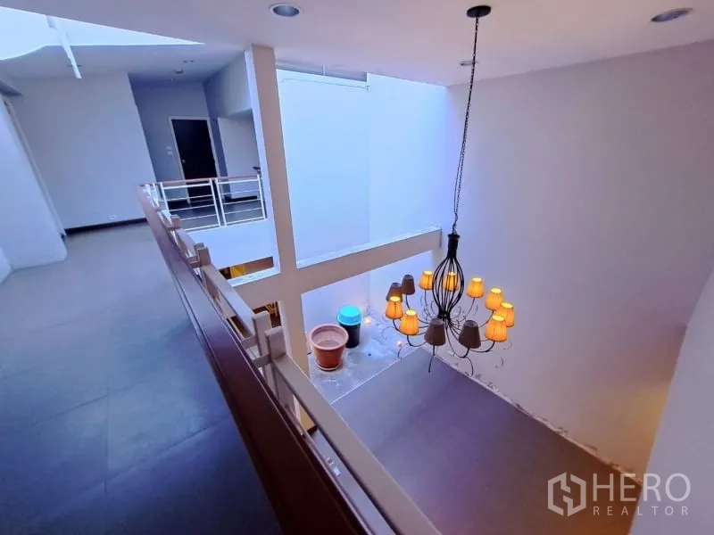 Shophouse for rent in Watthana, Bangkok - Mezzanine walkway overlooking atrium and decorative chandelier.
