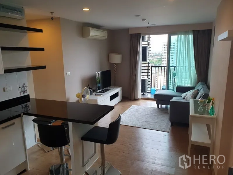 公寓 出租在Watthana, Bangkok - 采光良好的起居区，通向阳台与城市景观，旁有餐吧