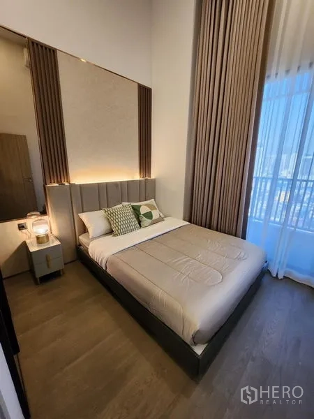 Condominium for rent - Second bedroom with tall curtains, upholstered headboard, and bright window.