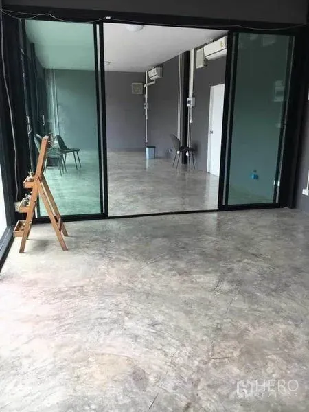 Home Office for rent in Din Daeng, Bangkok - Glass sliding partition dividing a bright concrete-floored workspace with AC and utility lines.